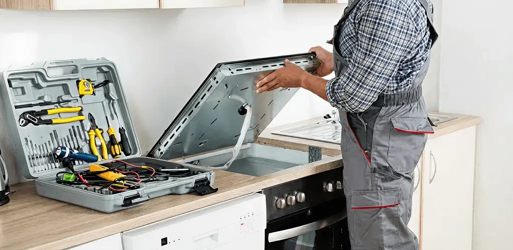 Handyman repairing a cooktop and checking wiring connections in Santa Ana, CA