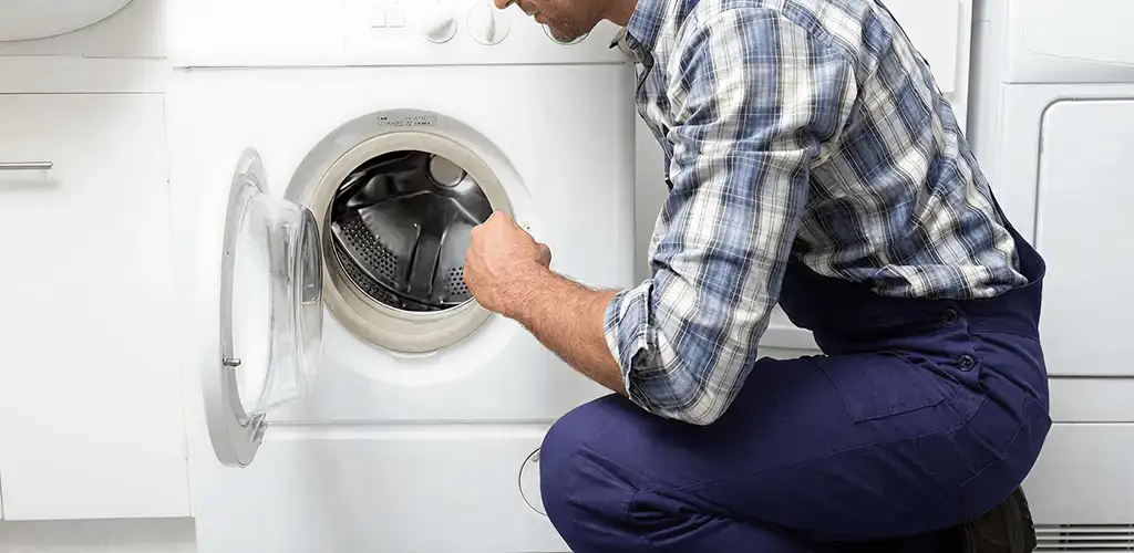 Handyman inspecting a dryer drum and internal parts for repair in Santa Ana, CA