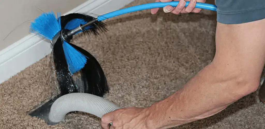 Dryer vent cleaning technician brushing lint from a vent line in Santa Ana, CA