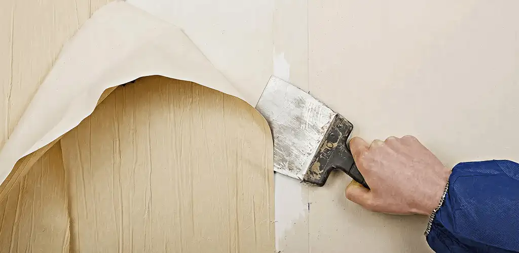 Handyman removing wallpaper with a scraper for wall preparation in Santa Ana, CA