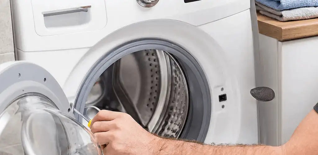 Handyman repairing a front-load washing machine and inspecting the drum in Santa Ana, CA