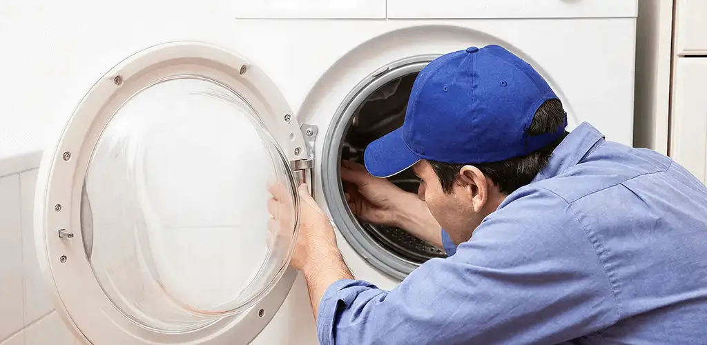 Washing machine repair handyman inspecting a front-load washer drum in Santa Ana, CA