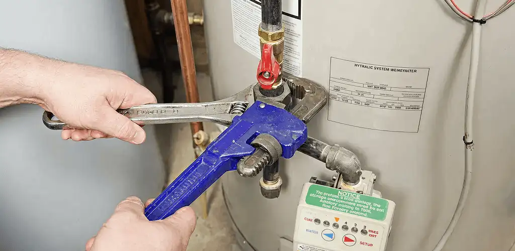 Water heater repair technician tightening the shutoff valve and supply line in Santa Ana, CA